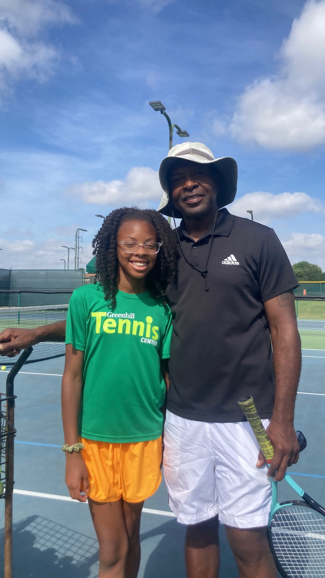 Coach Darryl Gee with a junior player courtside on a sunny day